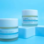 Close-up of skincare cosmetic jars on a modern blue backdrop.