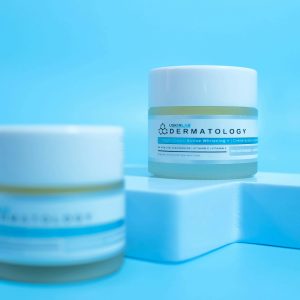 Close-up of skincare cosmetic jars on a modern blue backdrop.