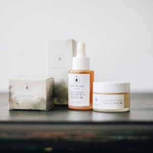 Elegant flat lay of natural skincare products, featuring a vitamin C serum and face balm.