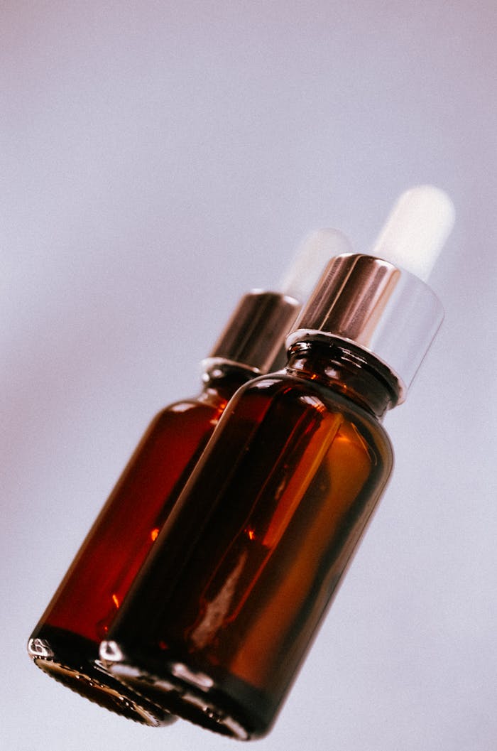 Elegant amber glass dropper bottles on a pastel background, perfect for skincare or essential oils.