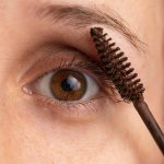 Detailed close-up of an eye applying mascara for makeup enhancement.