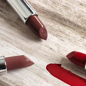Various shades of lipsticks arranged on a rustic surface. Ideal for beauty and cosmetic content.